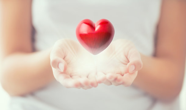 Gentle womens hands and a red heart glowing in his hands. Valentines mothers day and charity concept