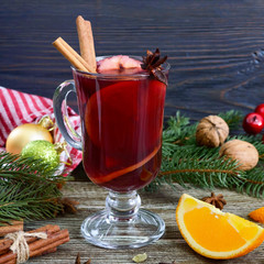 Hot mulled wine in glass mug on a wooden table. Fragrant traditional winter drink based on wine,...