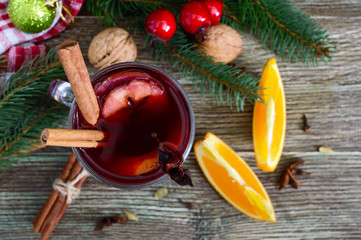 Hot mulled wine in glass mug on a wooden table. Fragrant traditional winter drink based on wine, juice, spices, seasonings, fruits. Close up. The top view