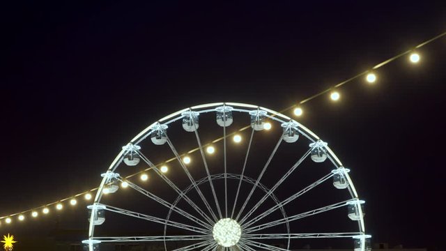 Part of beautifully lighted ferris wheel against a night sky background.