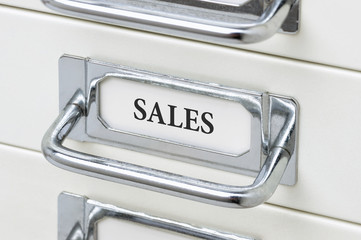 A drawer cabinet with the label Sales
