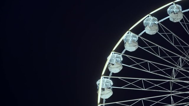 Part of beautifully lighted ferris wheel against a night sky background.