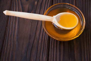 Honey dripping from honey dipper on yellow background. Thick honey dipping from the wooden honey...