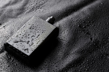 Black bottle of parfume with open cap on black water drops background.Closeu shot