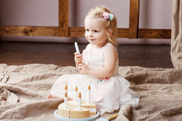 Child girl playing with a wooden toy cake. Little cute girl with  natural toys.