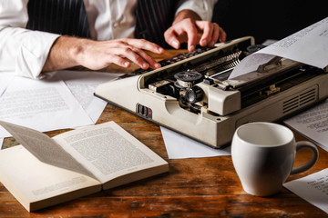 Young man's typing on an antique vintage typewriter, crop view
