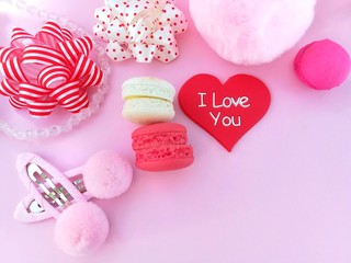 Delicious macaron decoration heart hair clib pom bow, crystal necklace and ribbon are placed on pink paper background, beautiful wallpaper