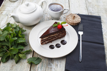 Delicious chocolate cake in white plate on wooden table background, closeup