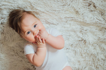 Cute baby putting hands in mouth and sucking fingers 