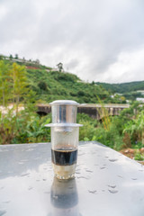 Fototapeta na wymiar Vertical photo of raditional Vietnamese milk coffee with mountain forests background