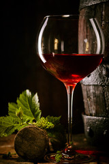 Red wine in a glass with vine leaves and cork