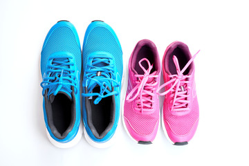 Pair of blue running sneakers for men and pair of pink one for women on white background.