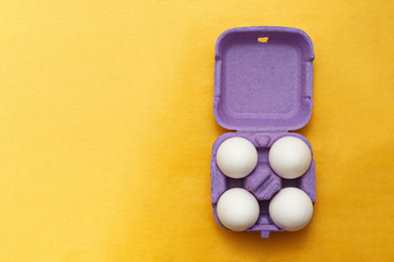 Easter composition. Set of Four white eggs in purple box on  yel