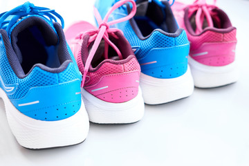 Pair of blue running sneakers for men and pair of pink one for women on white background.