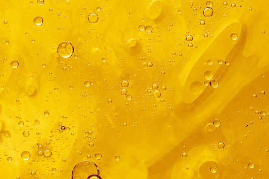 Abstract yellow background with oil drops and waves on water surface
