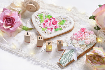 vintage style flat lay with a heart shaped cookie, laces and roses