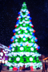 Colorful Defocused Christmas Tree Lights over city background and snow at night