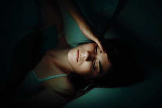 Woman in bed at night with smartphone
