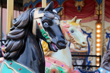 Fototapeta na wymiar Vintage carousel horses close-up on festive fair