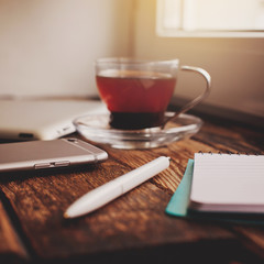 Smartphone and cup of tea on the wooden table.