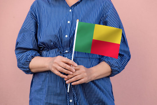 Benin flag. Close up of a woman's hands holding Benin flag. - Powered by Adobe