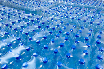 Fototapeta premium Many packaged blue mineral water bottles in stock in a store or market.