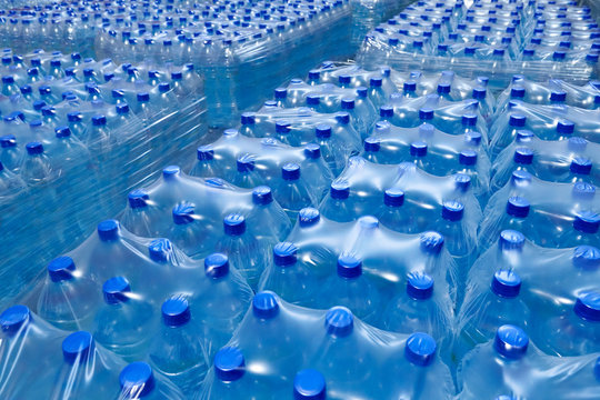 Many packaged blue mineral water bottles in stock in a store or market.