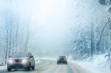 The car is driving through the snowy winter road. Cold weather in January and February.