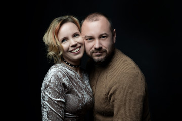 Romantic loving married couple of 30-40 years old are looking one way against a dark background.