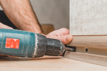 Technology of installation and installation of plastic floor plinth - the master mounts the holder...