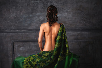 Beautiful girl with curls with a naked back. Back view