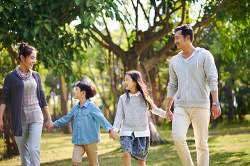 asian family with two children walking relaxing having fun in park