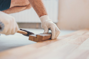 The master hammers the boards closer with a hammer - repair and finishing work