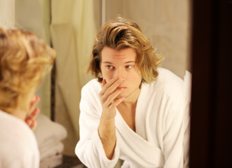 Applying the cream.young man looking in the mirror
