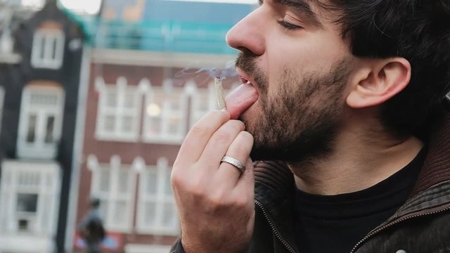 Close-up bearded man smoking a joint in the center of Amsterdam