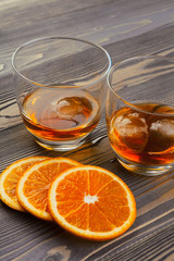 Whisky glass with orange fruit cut on dark wooden background