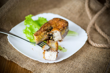 piece of fried pike fish in a plate on a wooden