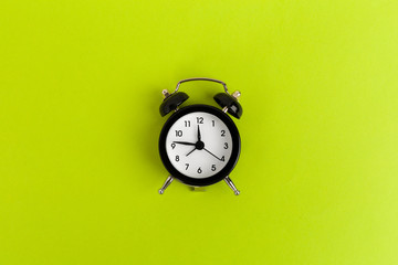 Vintage black alarm clock on a bright green background