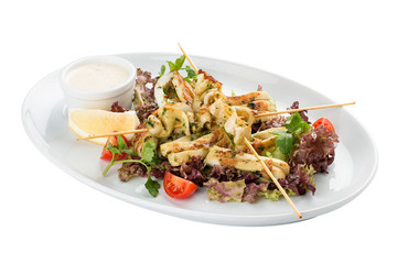Squid grilled on skewers, with salad and sauce. On white background