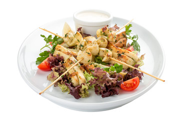 Squid grilled on skewers, with salad and sauce. On white background