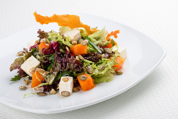Salad with pumpkin and feta on a white background. Vegetarian