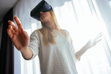 Young blonde at home with a modern design puts on virtual reality glasses