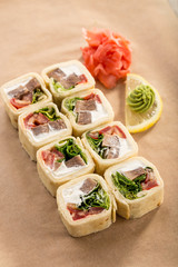 Delicious tortilla roll with beef, cheese and vegetables with ginger and wasabi on paper background