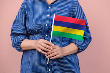 Mauritius flag. Close up of woman's hands holding Mauritius flag.
