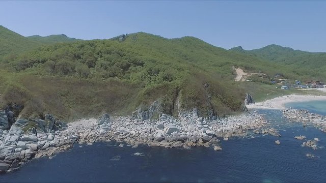Aerial shot moving along the coastline of deep blue sea along a dramatic cliff edge on sunny day