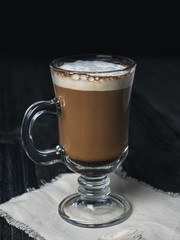 Irish coffee glass with foam and cinnamon on wooden table