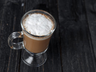Irish coffee glass with foam and cinnamon on wooden table
