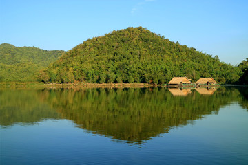 Fototapeta na wymiar Reflections of mountain ranges and the rafts on Hoob Khao Wong Reservoir, Suphanburi province, Thailand