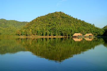 Obraz premium Reflections of mountain ranges and the rafts on Hoob Khao Wong Reservoir, Suphanburi province, Thailand