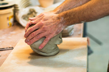 Artist potter in the workshop preparing material for sculpting ceramic vase. Hands closeup. Small...